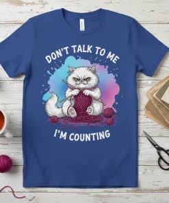 Don't Talk To Me I'm Counting t-shirt featuring a grumpy white cat knitting with yarn