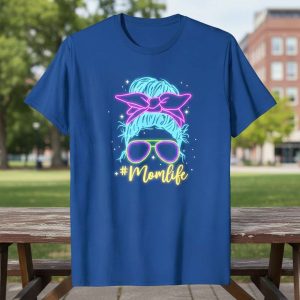 Neon #Momlife text with a messy bun and sunglasses graphic on a blue t-shirt